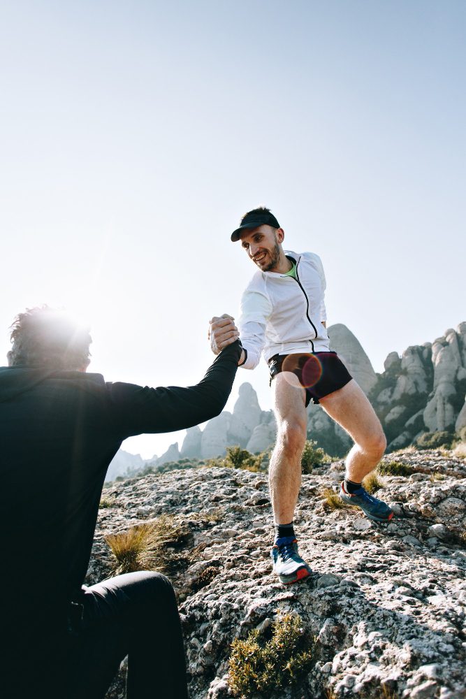 Deux coureurs s'entraident pour grimper un passage rocheux